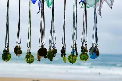 Close-up of necklaces hanging in a window overlooking the beach