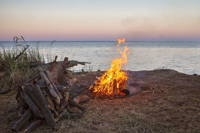 Panoramic view of bonfire on beach against sky during sunset