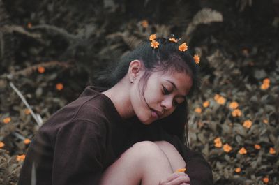 Young woman looking away while sitting on land