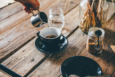 Close-up of hand pouring water into coffee cup on table