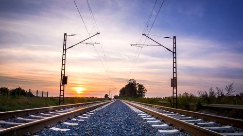 Railroad tracks against sky during sunset