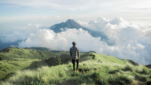 Rear view of man standing on field against mountains