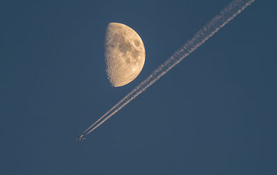 Low angle view of airplane against  moon and clear sky at night