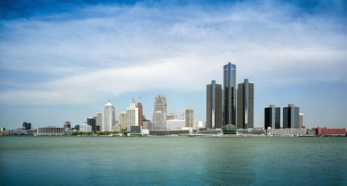 City at waterfront against cloudy sky