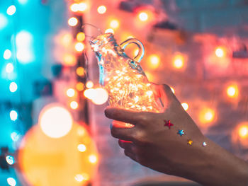 Close-up of hand holding illuminated christmas lights