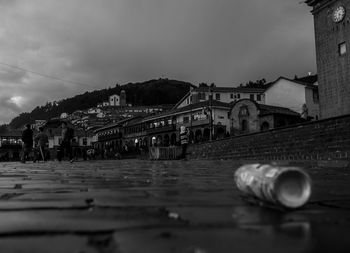 Drink can on wet street against buildings at dusk