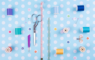 Directly above shot of sewing item arranged on blue polka dot background