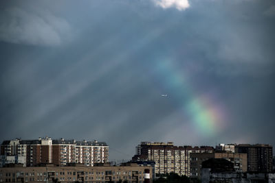 Low angle view of buildings against rainbow sky