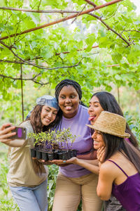 Portrait of smiling young woman standing against trees