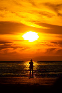 Silhouette woman walking at beach during sunset