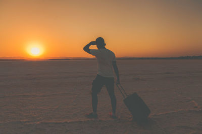 Silhouette man standing on beach against sunset sky