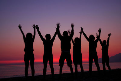 Silhouette people standing on land against sky during sunset