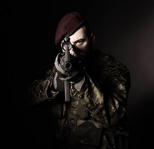 Portrait of young man wearing mask against black background