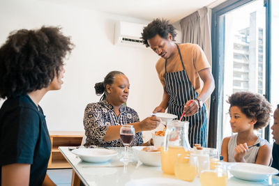 Man serving food to family at dining table