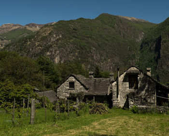 Houses on grassy field against mountain