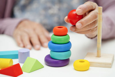 Cropped hand of woman holding multi colored toy blocks on table