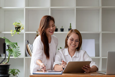 Smiling young woman using smart phone at home