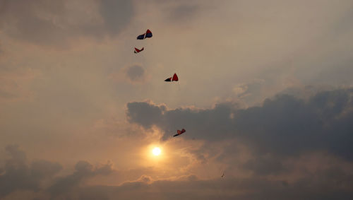 Low angle view of silhouette kite against sky during sunset
