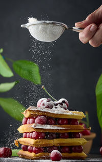 Stack of baked belgian waffles with ripe red cherries sprinkled with powdered sugar, breakfast