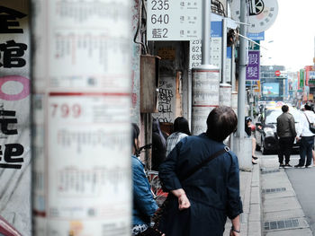 Rear view of people walking on street in city