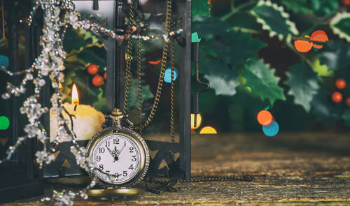 Close-up of pocket watch by candle on table