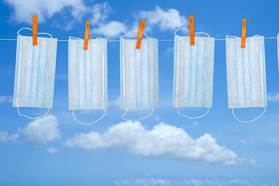 Low angle view of clothesline hanging against blue sky