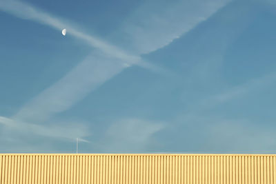 Low angle view of yellow wall against blue sky