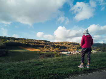 Rear view of woman standing on field against sky