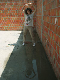 Full length of girl standing against brick wall