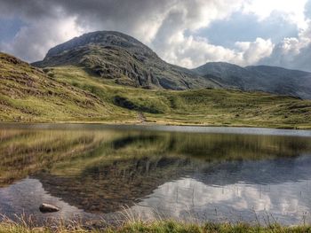 Scenic view of lake and mountains against dramatic sky