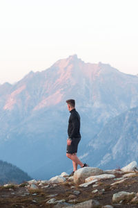 Full length of young man standing on rock against sky