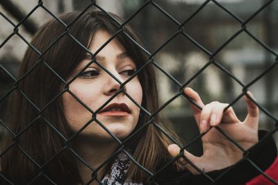 Portrait of man seen through chainlink fence