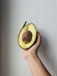 Close-up of hand holding fruit against wall