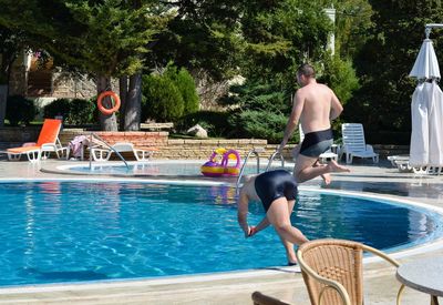 Man jumping in swimming pool against trees