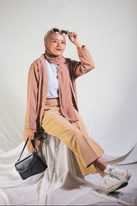 Full length of woman wearing hat while standing against wall