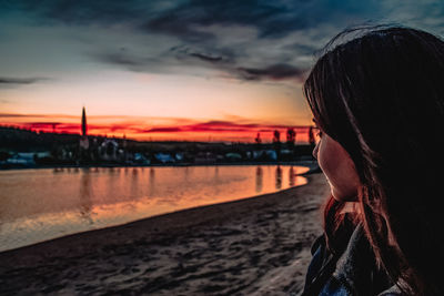 Portrait of woman on beach against sky during sunset