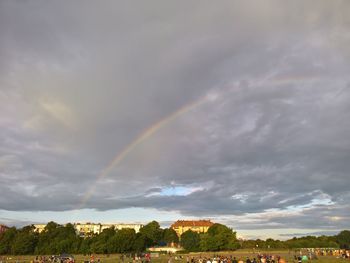 Rainbow over landscape against cloudy sky