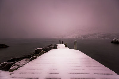 Pier over sea against sky at dusk