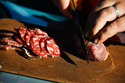 Close-up of person preparing meat on barbecue grill