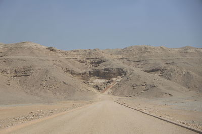 Road amidst desert against clear sky