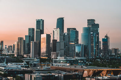 Modern buildings in city against sky during sunset