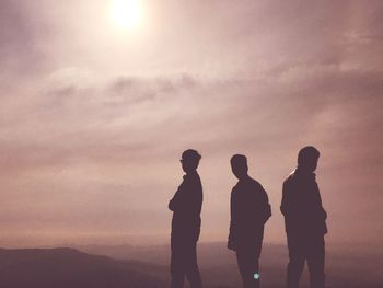 Silhouette people standing on mountain against sky during sunset