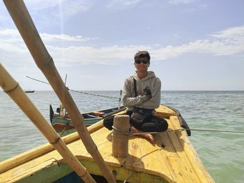 Man sitting on boat in sea against sky