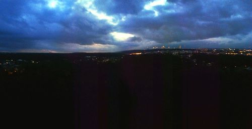 Illuminated cityscape against cloudy sky