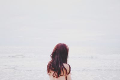 Rear view of naked woman at beach against sea