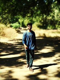 Full length portrait of happy young man on road