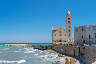 Building by sea against clear blue sky