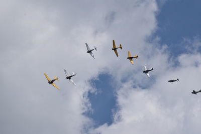 Low angle view of airplanes flying against cloudy sky