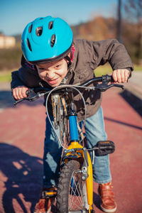 Boy riding bicycle on road in city during sunny day