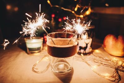 Close-up of burning sparklers in drinking glass on table